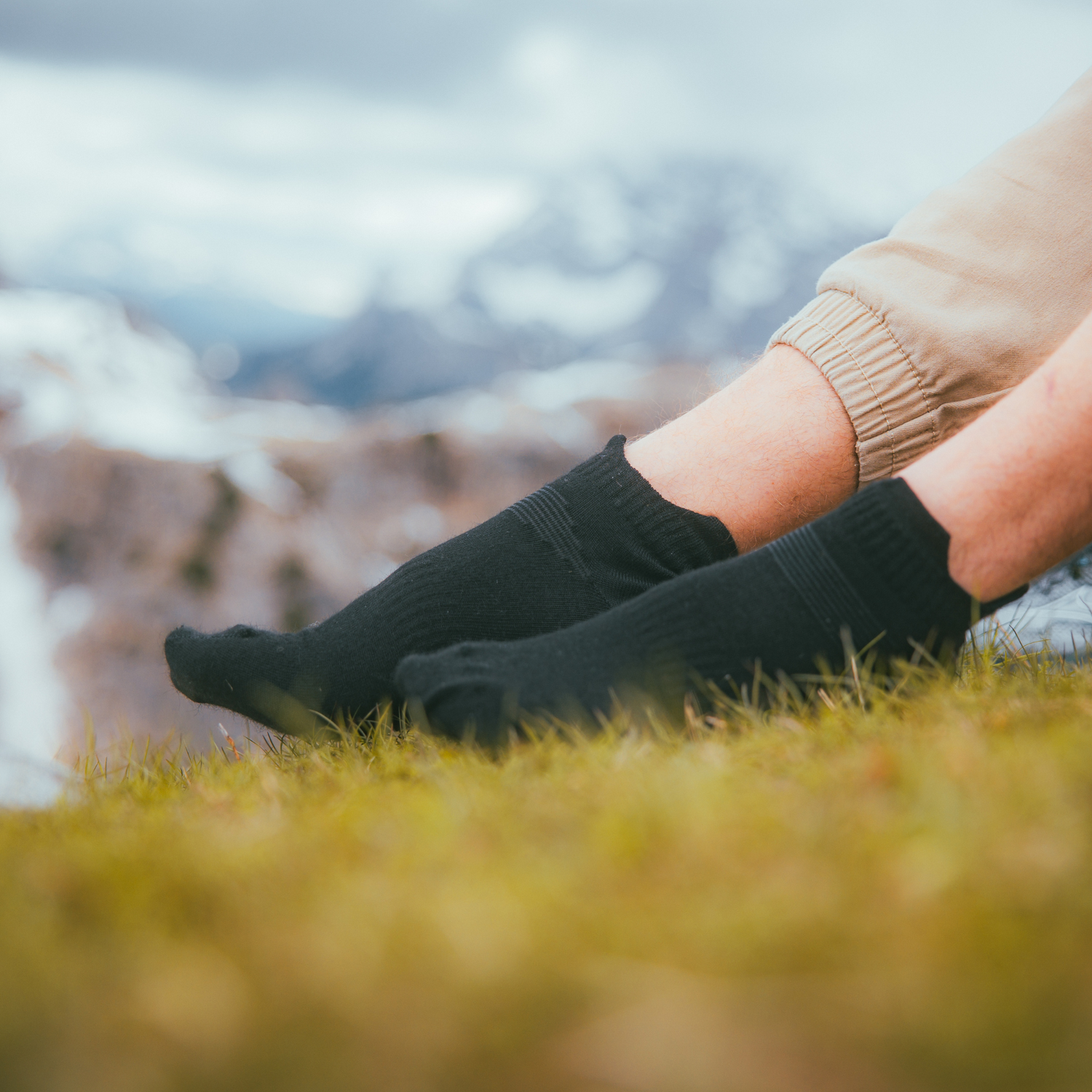 Liito_alpacawool_black_ Relaxed black alpaca wool socks by Liito, worn on a man's feet while resting in nature