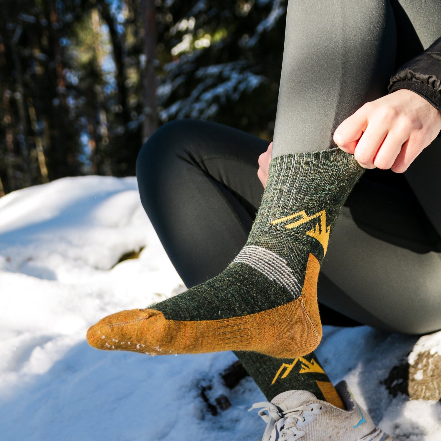 Person wearing green and Yellow hiking socks with a snowy forest background