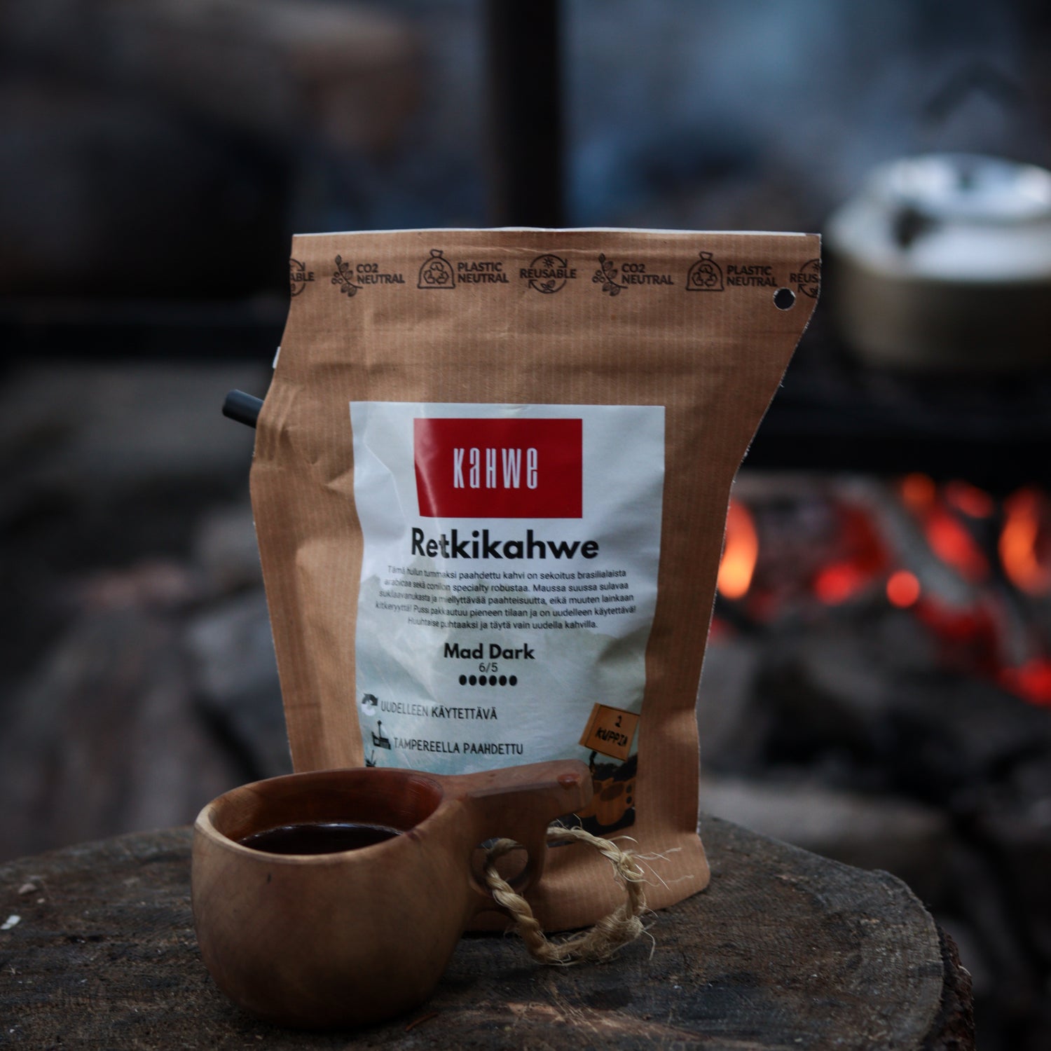 tumma_paahtoinen_retkikahvi_paketissa_taustalla_nuotio