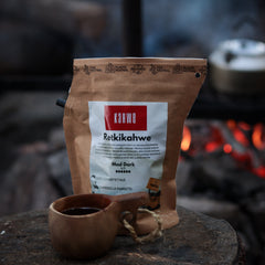 tumma_paahtoinen_retkikahvi_paketissa_taustalla_nuotio